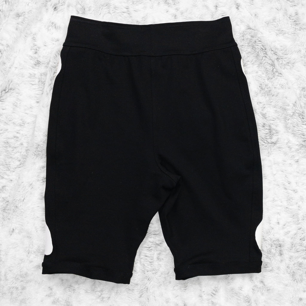 A flat lay image showcasing the back of a black 4-way stretch ponte knit bike shorts with femur bone appliqué along the side seams. The shorts feature soft, luxurious fabric in an inky black. The background is neutral, highlighting the shorts' details and textures.