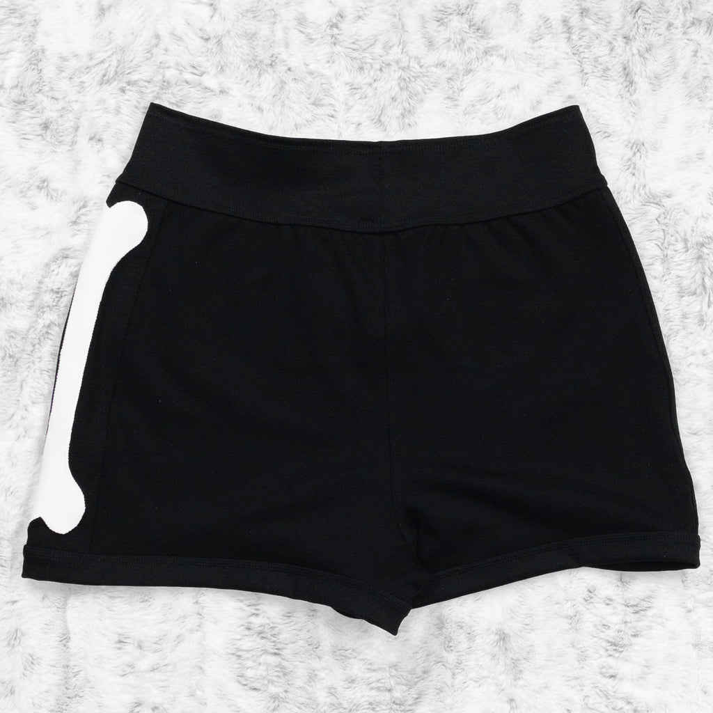 A flat lay image showcasing the back of a black 4-way stretch ponte knit bike shorts with femur bone appliqué along the side seams. The shorts feature soft, luxurious fabric in an inky black. The background is neutral, highlighting the shorts' details and textures.