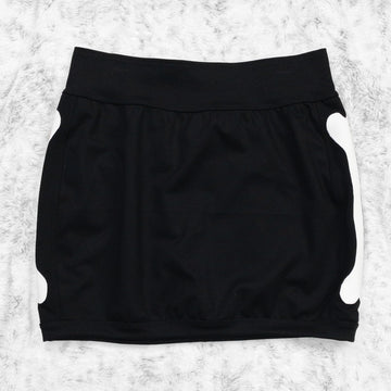 A flat lay image showcasing a black 4-way stretch ponte knit mini skirt with femur bone appliqué along the side seams, showcasing a stylish and unique design. The skirt features soft, luxurious fabric in an inky black. The background is neutral, highlighting the skirt's details and textures.