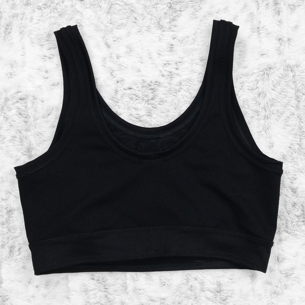 A flat lay image showcasing the back of a black 4-way stretch ponte knit scoopneck close cut crop with princess seams and a ribcage appliqué on the centerfront. The top features soft, luxurious fabric in an inky black. The background is neutral, highlighting the shorts' details and textures.